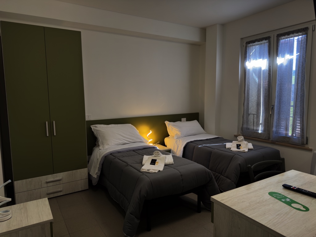 Camera luminosa con letti e arredi moderni di Colle Muzia